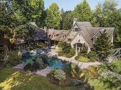 an aerial view of a house with a pool in the front yard and trees surrounding it