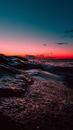 the sun is setting over the ocean with birds flying in the sky and water splashing on the beach