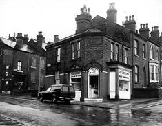 an old black and white photo of a street corner with cars parked on the side