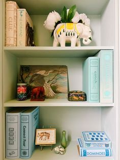 a shelf with books, figurines and other items on it in a room