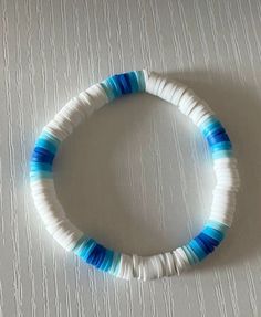 a white and blue beaded bracelet sitting on top of a table