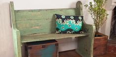 a green bench with a pillow on it next to a potted plant and wooden drawers