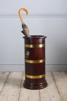 an umbrella sticking out of the top of a wooden trash can on a wood floor