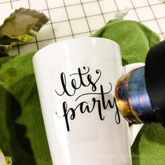 a white coffee mug with the words let's party on it next to a green towel