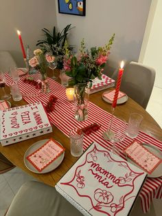 the table is set with red and white place mats, plates, candles, and flowers