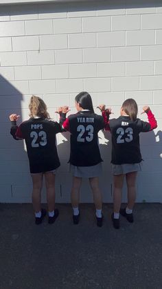 three girls wearing black shirts with numbers on them