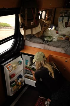 a woman sitting in front of an open refrigerator