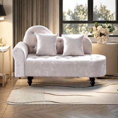 a white couch sitting on top of a wooden floor next to a table with flowers