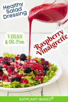 a salad with berries, raspberry vinaigrete and dressing being poured onto it