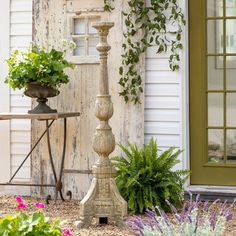 an old fashioned water fountain in front of a house with potted plants on it