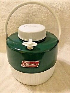 a green and white ice bucket with a handle on the top, sitting on a towel