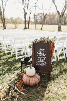 a chalkboard sign sitting on top of a grass covered field next to white chairs