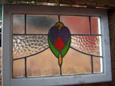 a close up of a stained glass window on a brick wall with trees in the background