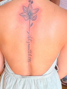 the back of a woman's neck with a flower tattoo on it