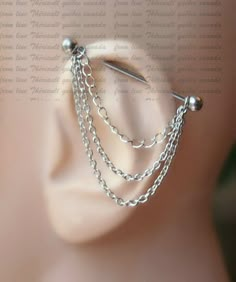 a close up view of a silver ear with chains attached to the back of it