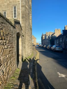 the shadow of a person standing in front of an old stone building on a street