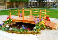 a wooden bridge over a small pond filled with flowers