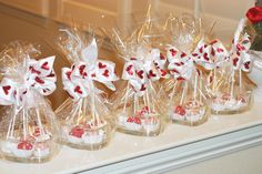 small clear vases filled with candy canes on a counter next to a red rose