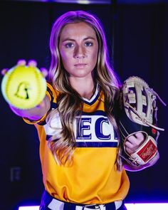 a woman holding a yellow softball in her right hand and wearing a catchers mitt