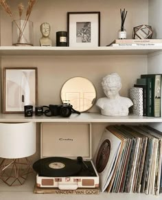 an old record player is sitting on top of a book shelf next to a lamp