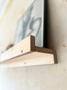 a close up of a wooden shelf with a framed photo on the wall behind it