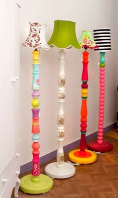 three colorful lamps sitting next to each other on a wooden floor in front of a white wall