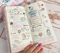 a hand holding an open planner book with stickers on it