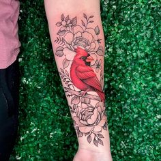 a woman's arm with a red bird on it and flowers around the wrist