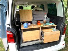 the back end of a white van filled with wooden drawers and storage boxes on it's trunk