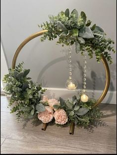 a wreath with candles and greenery hanging from the side on top of a wooden floor