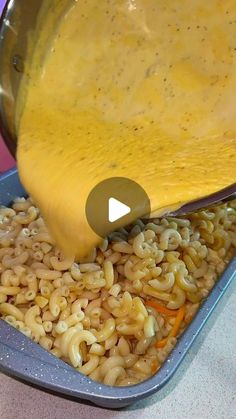 someone is pouring cheese on some macaroni and cheese in a pan with carrots