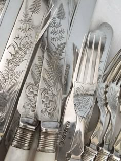 an assortment of antique silverware including forks, knives and spoons with floral designs