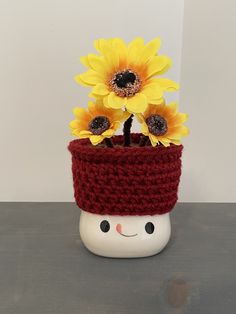 a crocheted pot with sunflowers in it and a smiling face on the side