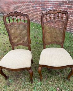 two chairs sitting in the grass near a brick wall