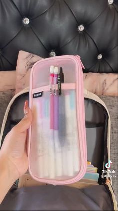 a person holding a pink case filled with pens