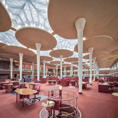 the interior of a library with tables and chairs, large skylight above it's ceiling