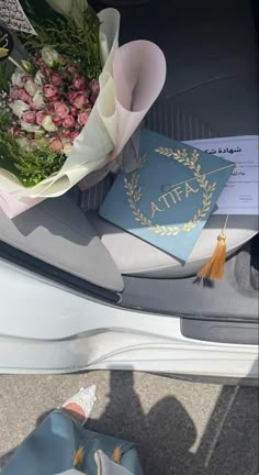 flowers are placed on the trunk of a car, next to a passport and other items