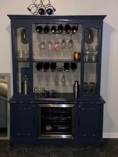 a blue china cabinet with wine glasses on top