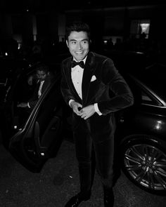 a man in a tuxedo standing next to a car