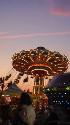 people at an amusement park with rides and carousels in the background during sunset or dawn