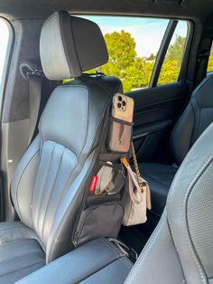 the back seat of a car with a cell phone and purse hanging from it's holder