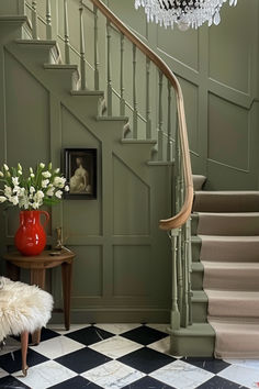 a staircase with chandelier and flowers in vases on the table next to it