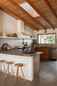 a kitchen with three stools in front of the counter and an oven on the other side