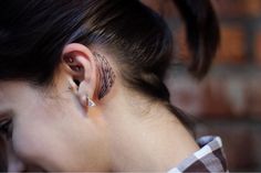 a woman with ear piercings on her ears and behind her ear is a brick wall