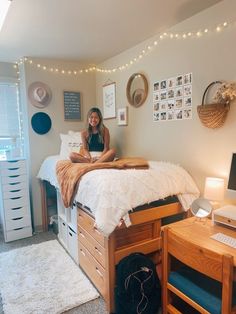 a woman sitting on top of a bed next to a desk with a laptop computer