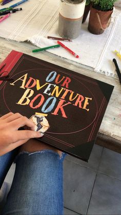 a person sitting at a table with a book in front of them that says our adventure book