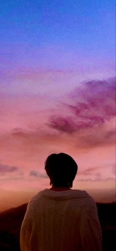 a person standing in front of a purple and blue sky