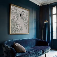 a living room with a blue couch and painting on the wall