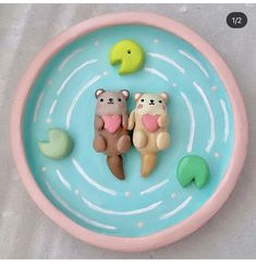 two bears are sitting in the water on a blue plate with green and yellow decorations