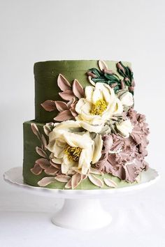 there is a green cake with flowers on the top and bottom layer, decorated with leaves